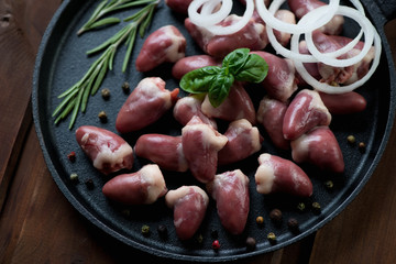 Closeup of raw fresh chicken hearts with seasonings, studio shot