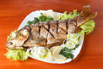 Roasted carp fish with vegetables entirely. Traditional Christmas meal.