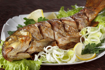 Baked carp fish with vegetables entirely. Traditional Christmas menu.