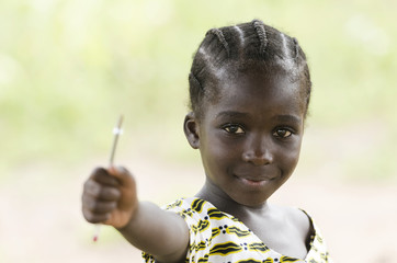 Education symbol: little African black teenage girl holding pen in the air lightly smiling to the camera. African children need education since it is the most important thing for a better future.