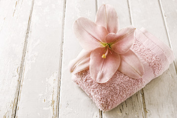 Pink lily flower and soft towel on wooden background