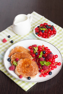 sweet cheese pancakes with fresh berries and milk on black woode