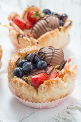 Tartellette di pasta sfoglia riempite di crema e frutta fresca sul tavolo
