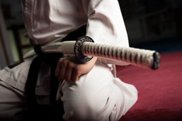 Close up van jonge vechtsportvechter met katana aanbrengen in seiza-positie
