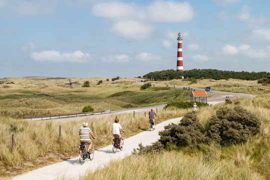 Seniors riding on bicycles in the dunes of Ameland near the lighthouse, Netherlands