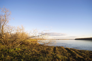 The scenery on the Ob river with a floating barge in the distance