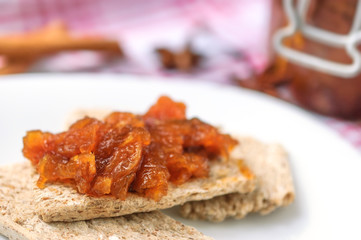 Canapes with homemade onion chutney with ginger and red pepper on a white plate. Selective focus on a chutney.