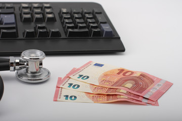 Stethoscope,money, keyboard on white, medical concept.