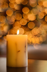 Vela encendida con luces de Navidad desenfocadas de fondo