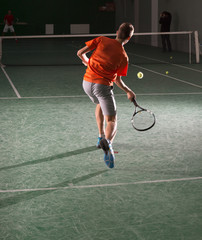 Young tennis player kicking the bal