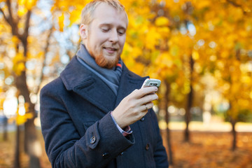Fototapeta premium a man in a coat talks on the phone in the autumn park