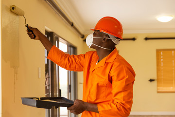 african construction worker painting the wall
