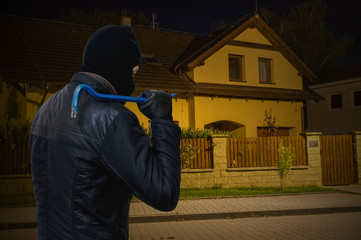 Masked bandit or criminal is going to rob house at night.
