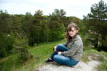 Young girl sitting on a hill in the forest. Meditation