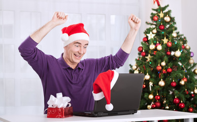 Happy smiling senior man with santa claus hat shopping online