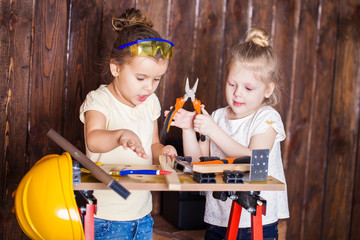 Two little girls making very interesting creations with tools and wood at home