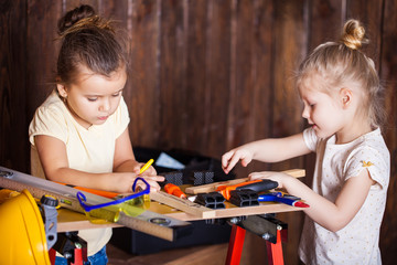 Two little girls making very interesting creations with tools and wood at home