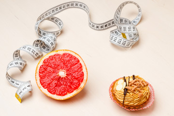 Grapefruit and cake with measuring tape. Diet
