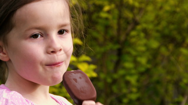 Ein kleines M&auml;dchen isst im Gr&uuml;nen Eis am Stil - Teil 1