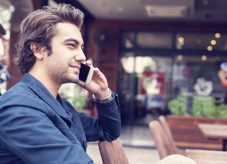 Young man talking phone in cafe