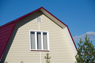 New country house with beige siding and and white plastic window  on sunny day closeup
