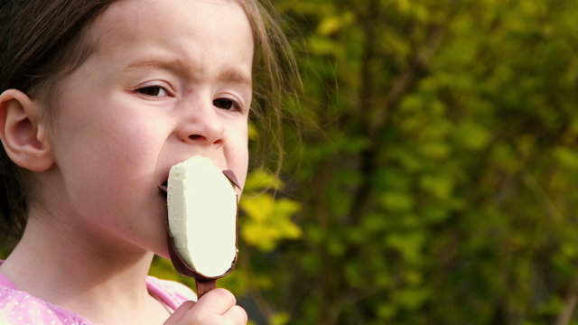 Ein kleines M&auml;dchen isst im Gr&uuml;nen Eis am Stil - Teil 3