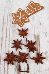 Christmas tree shape made of anise and decorated gingerbread on old wooden background