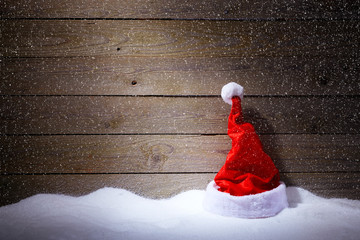 Santa hat in snow on wooden background