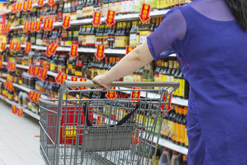 Lady pushing a shopping cart in the supermarket.