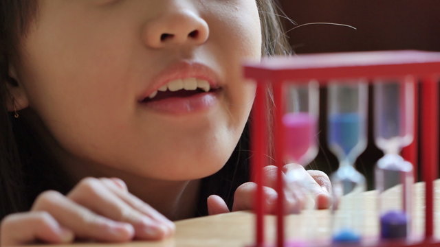 Little Asian child looking at hourglass in class