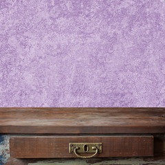 Empty wooden table against a lilac wall.