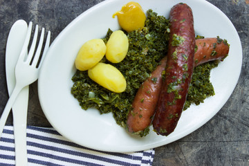 Original Grünkohl mit Pinkel, Kartoffeln, Senf, blauweiße Serviette, Besteck, auf Grau