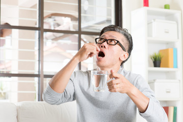 Mature 50s Asian man eating medicine