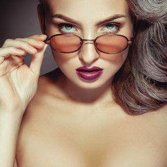 Closeup photo of beautiful woman in trendy sunglasses and makeup