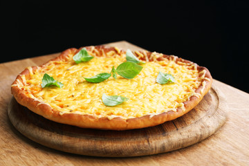 Tasty cheese pizza with basil on black background
