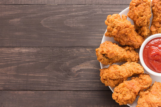 fried chicken drumstick and ketchup on wooden background