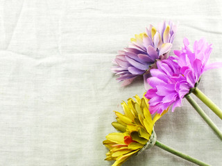 arrangement of artificial gerbera flowers located on burlap background useful as invitations