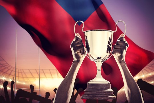 Composite image of cropped hand of athlete holding trophy