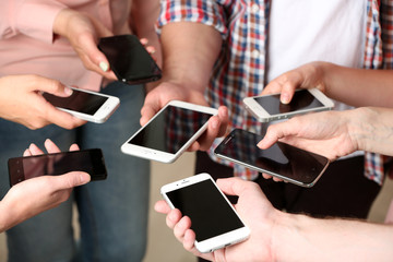 Many hands holding mobile phones close up