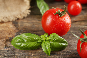 Cherry tomatoes with basil on wooden table close up