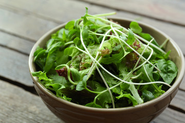 Fresh mixed green salad in bowl on wooden table close up