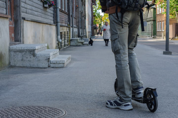 Young man in casual wear on kick scooter on street