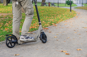Obraz premium Young man in casual wear on kick scooter on street