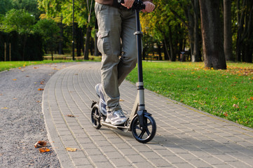 Obraz premium Young man in casual wear on kick scooter on street
