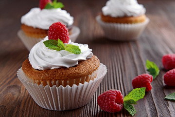 Delicious cupcakes with berries and fresh mint on wooden table close up