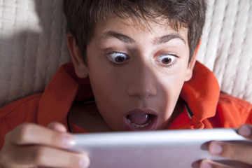 Surprised young boy is playing with tablet PC © COSPV