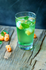 Glass of cold refreshing summer drink with berries and ice cubes on table close up