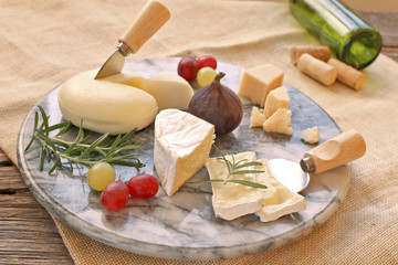 Marble board with various cheese , grapes, figs on sackcloth background 