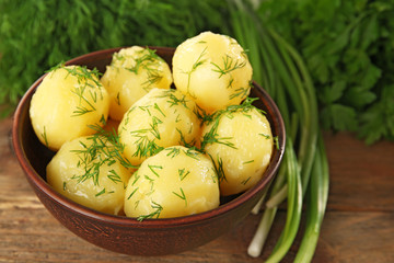 Boiled potatoes with greens in bowl on table close up