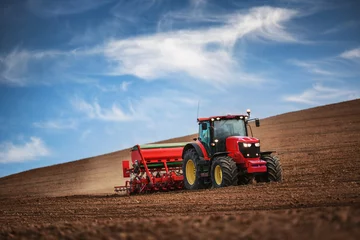Fotobehang Tractor Boer met tractor die gewassen zaait op het veld